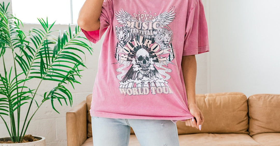 A woman modeling an oversized pink graphic band T-shirt with a vintage-inspired print.
